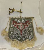 A needlework and beadwork pennant hung on brass frame