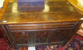 A 17th Century oak coffer, the three plank top with cleated ends over a carved three panel front