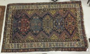 A Caucasian rug, the six diamond shaped central medallions in shades of terracotta, madder,