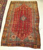 A Caucasian rug, the central diamond shaped medallion in teal, cream and dark red, on a red,