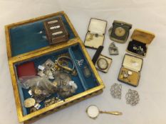 A jewellery box containing assorted costume jewellery, together with a silver buckle, a silver charm