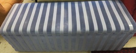 A blue striped upholstered ottoman with brass handles
