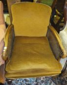 A 1920's walnut framed double caned Bergere armchair on cabriole front legs to pad feet