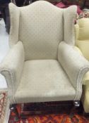 A circa 1900 upholstered wing back scroll arm chair on cabriole front legs in the George III taste