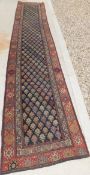 A Persian runner, the centre field with repeating stylised floral motifs in pink, blue, red,