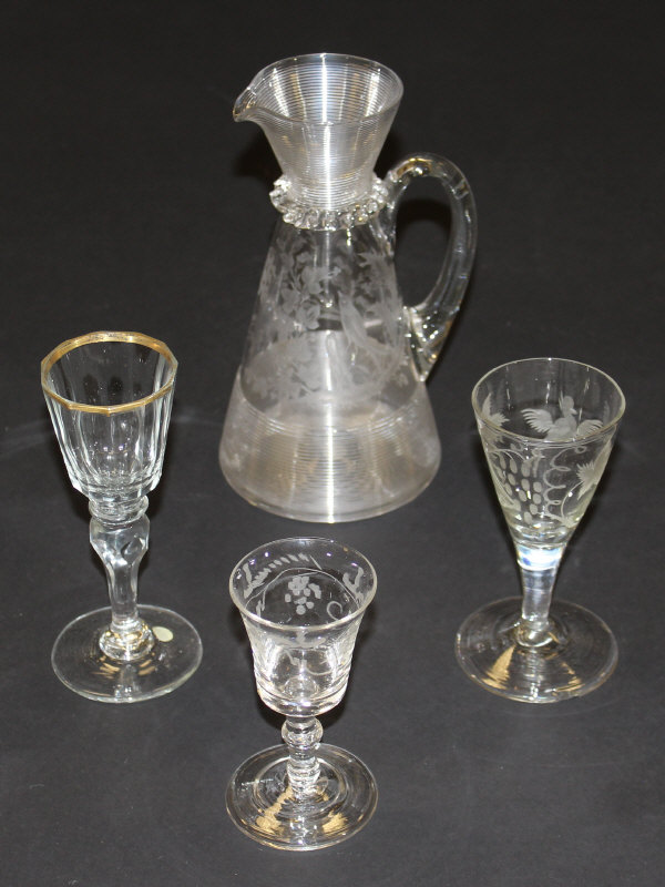 A late 19th Century glass jug with ribbed top and bottom sections and floral and bird engraving,