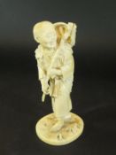A Meiji period Japanese carved ivory okimono of an elderly gentleman carrying a stick and basket and