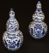 A pair of Chinese porcelain gourd shaped vases and covers, each painted in underglaze blue with