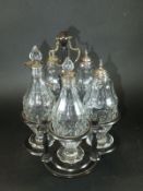 A Georgian ebonised cruet frame containing five cut glass bottles, each with silver mounts,
