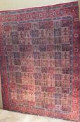 A Persian carpet, with all-over decoration of repeating square medallions in red,