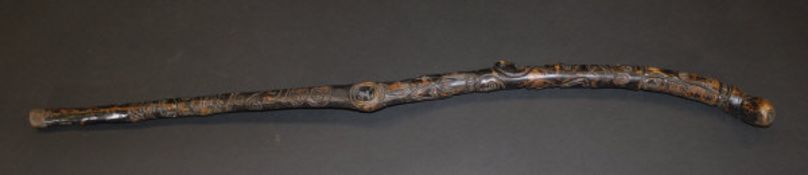 A 19th Century Northern European carved and stained wooden stick with all-over face mask, skull,