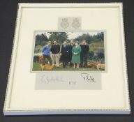 A framed and glazed image of the Royal Family in garden setting with corgis adapted from the 1979