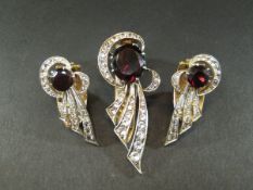 A pair of garnet and diamond set earrings in the form of stylised ribbons, together with a