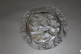 An Arts and Crafts style pewter charger with central gryphon embossed decoration,