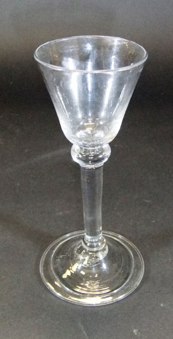 An 18th Century wine glass with funnel shaped bowl and knop to the top of the straight stem with