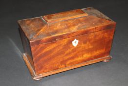 An early Victorian mahogany tea caddy of sarcophagus form, the lid opening to reveal a parquetry