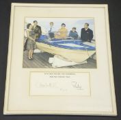 A framed and glazed image of the Royal Family around a speedboat on the Royal Yacht Britannia