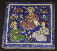 A 19th Century Quajar polychrome decorated tile depicting three seated figures in relief in a