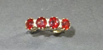 A four stone garnet and yellow metal dress ring,