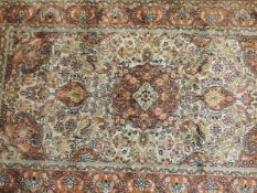 A Persian silk rug, the central floral decorated medallion in terracotta, cream,