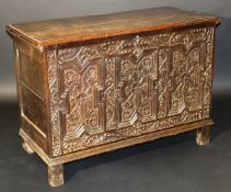 An 18th Century oak coffer, the two plank top with moulded edge above an oak leaf and acorn carved