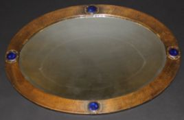 An Art Nouveau planished copper framed oval mirror in the Liberty manner, set with Ruskin type