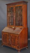 An early 19th Century mahogany bureau with blind fretwork to the cornice enclosing shelves,