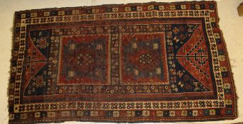 A Kazak rug, the two central square medallions in terracotta, dark blue and cream on a dark blue,