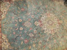 A Persian carpet, the central floral medallion in cream, salmon, pale yellow and pale green on a