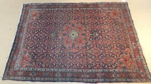 A Persian rug, the central salmon medallion with entwined floral decoration in red,