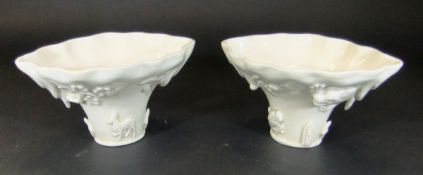 A pair of Chinese blanc-de-chine libation cups in the form of a rhinoceros horn and relief decorated