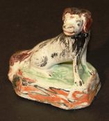An 18th Century miniature Delft figure of a seated dog upon a rectangular base with canted