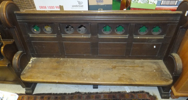 A carved oak church pew with pierced back