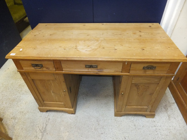 A waxed pine double pedestal desk of three drawers over two cupboard doors on bracket feet