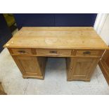 A waxed pine double pedestal desk of three drawers over two cupboard doors on bracket feet