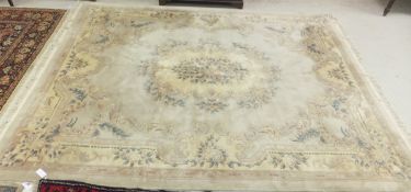 A Chinese superwash carpet with centre medallion on a beige ground within a floral decorated border,