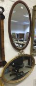 An early 20th Century giltwood and gesso framed oval wall mirror with bevel edged plate and ribbon