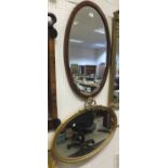 An early 20th Century giltwood and gesso framed oval wall mirror with bevel edged plate and ribbon