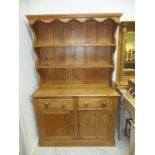 A pine dresser, the two tier boarded plate rack over two drawers and two cupboard doors,