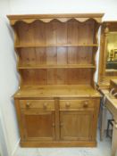 A pine dresser, the two tier boarded plate rack over two drawers and two cupboard doors,