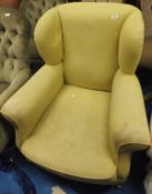 A circa 1900 wingback armchair in pale yellow upholstery on bun feet