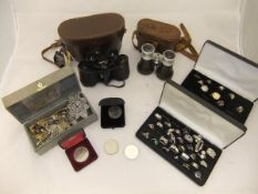 A box containing various white and yellow metal dress rings, two pairs of binoculars,