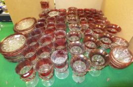 A large near-matching suite of cranberry decorated pressed glasses and plates,