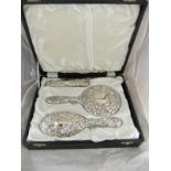 A silver mounted cased dressing table set comprising two hairbrushes and a hand mirror,