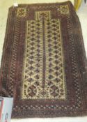 A Beluche prayer rug with central foliate decoration on a beige ground within a multiple plum