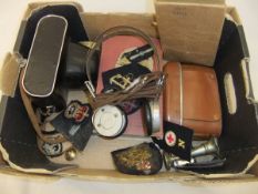 A box containing assorted cameras, cloth military arm badges, a pair of field headphones, bible,