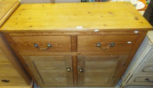 A pine sideboard of two short drawers over two cupboard doors on a plinth base