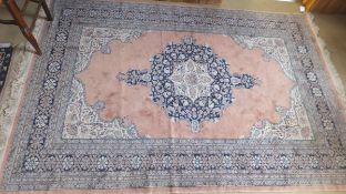 An Oriental style rug, the central floral decorated medallion in dark blue, cream and salmon,