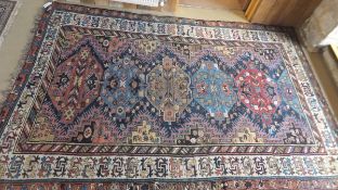 A Caucasian rug, the six diamond shaped central medallions in shades of terracotta, madder, blue and