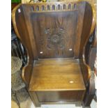 A 20th Century oak carved wing back box seated lambing style chair/settle